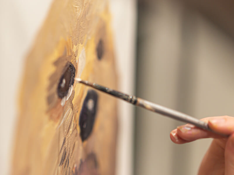 Hand with a paintbrush painting a dog portrait